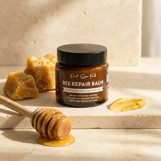 Jar of 'Bee Repair Balm' with honeycomb and honey dipper on a light background