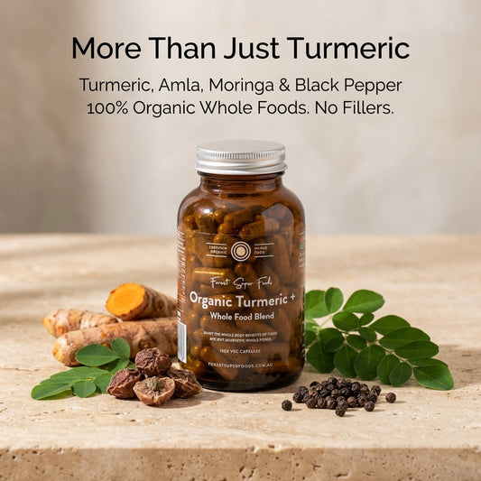 Bottle of Organic Turmeric Whole Food Blend with turmeric roots, amla berries, and black pepper on a wooden surface.