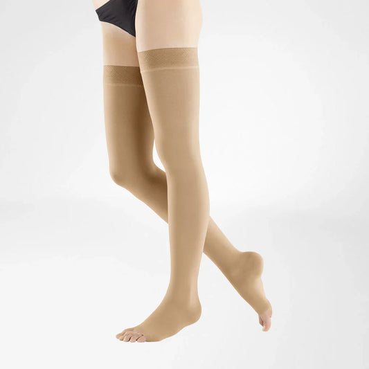 A pair of sheer beige thigh-high stockings worn on a model's legs, shown against a clean white studio background.
